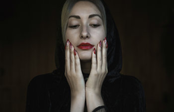 woman in vampire costume on halloween touching her face