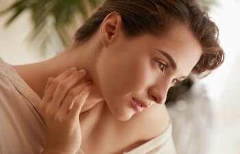 Beauty Face. Portrait Of Woman Touching Neck And Looking Away. Beautiful Model Enjoying Radiant And Glowing Facial Skin. Tender Brunette With Natural Makeup.